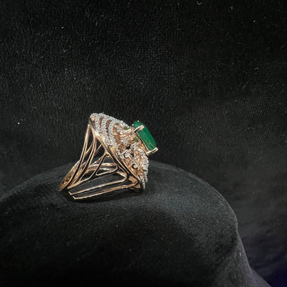 Close-up of an elegant statement ring featuring a large oval green gemstone at the center, surrounded by concentric circles of sparkling white diamonds set in a gold base against a black background.