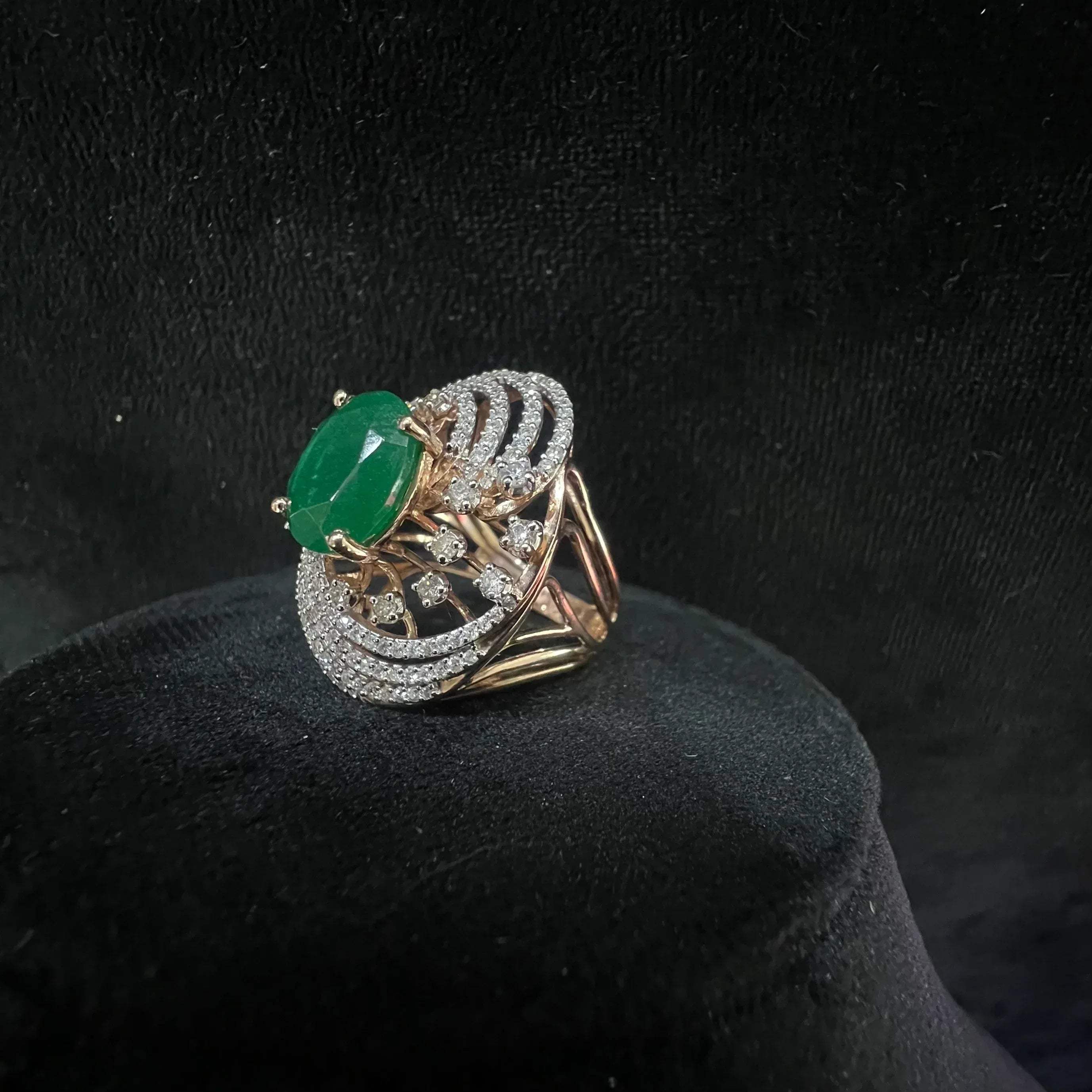 Close-up of an elegant statement ring featuring a large oval green gemstone at the center, surrounded by concentric circles of sparkling white diamonds set in a gold base against a black background.