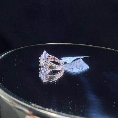 A gold band ring with central diamonds, surrounded by smaller diamonds set in the band is displayed on a reflective surface.