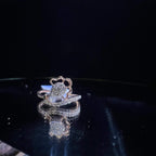 A gold band ring with a central natural diamond, surrounded by smaller clear stones displayed on a reflective surface.
