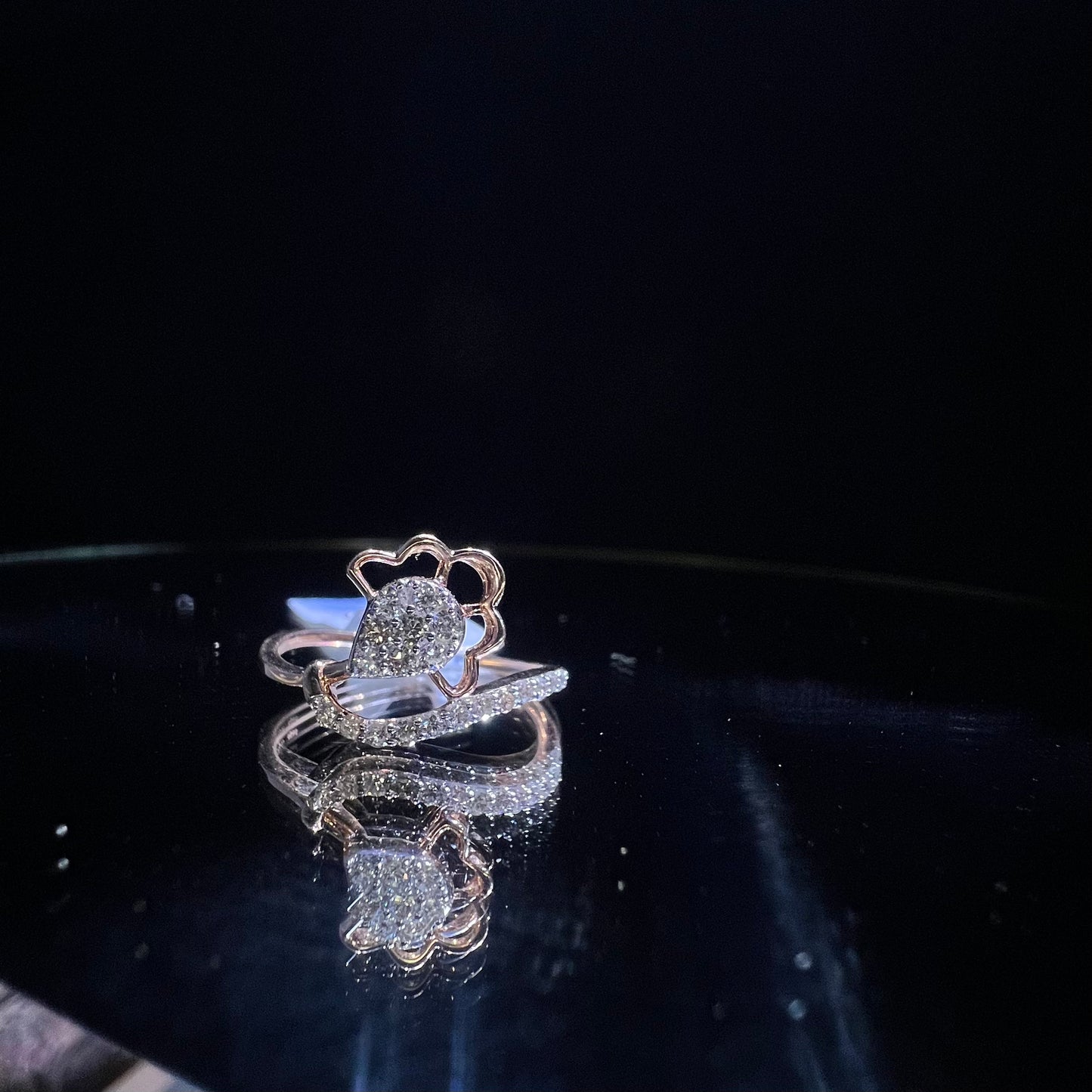 A gold band ring with a central natural diamond, surrounded by smaller clear stones displayed on a reflective surface.