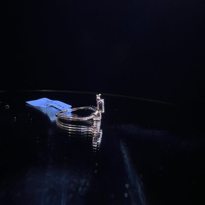 A gold band ring with a central natural diamond, surrounded by smaller clear stones displayed on a reflective surface.