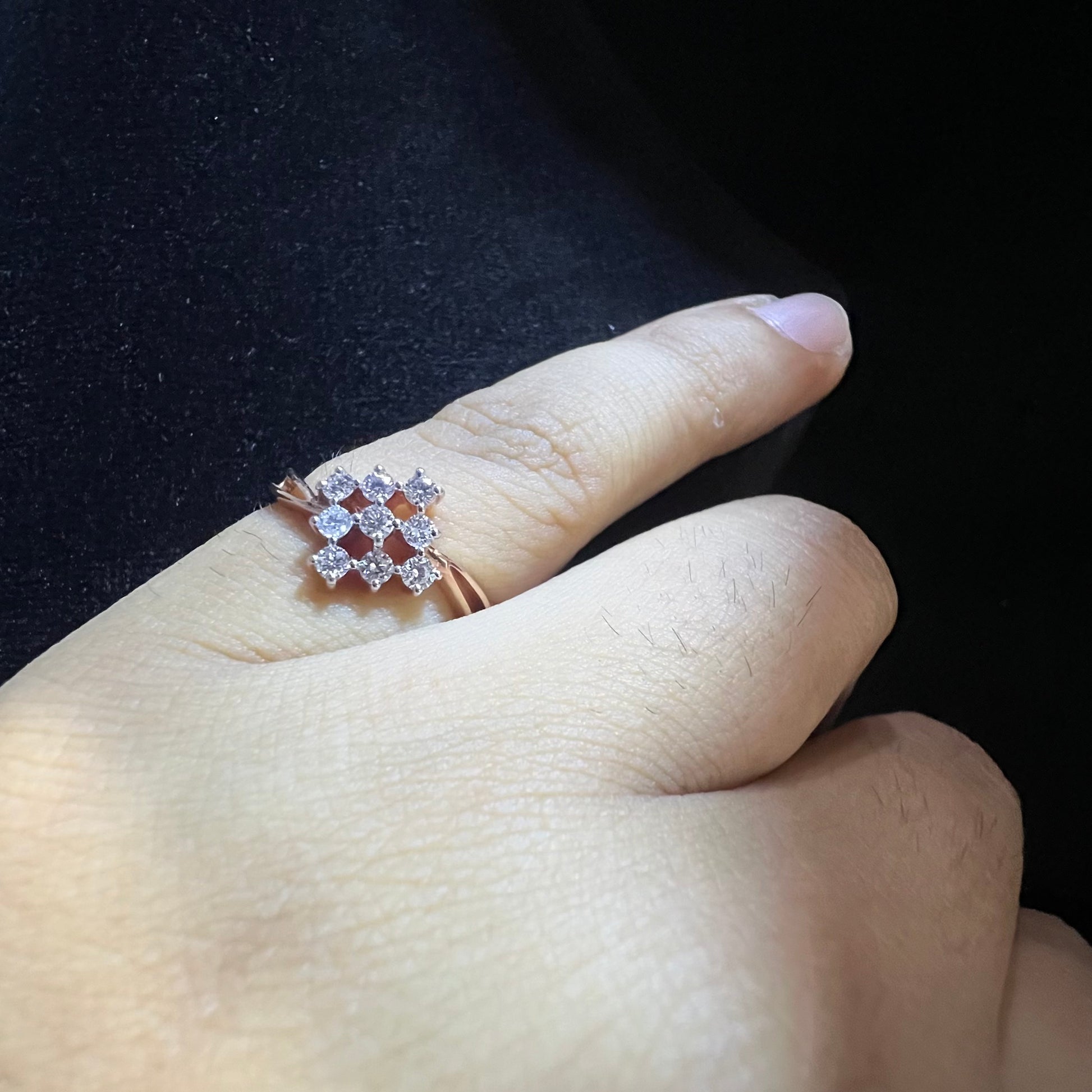 A handcrafted natural diamond solid gold ring, held on a person's finger, showcasing the ring's design and the shine of the diamonds.