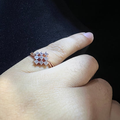 A handcrafted natural diamond solid gold ring, held on a person's finger, showcasing the ring's design and the shine of the diamonds.