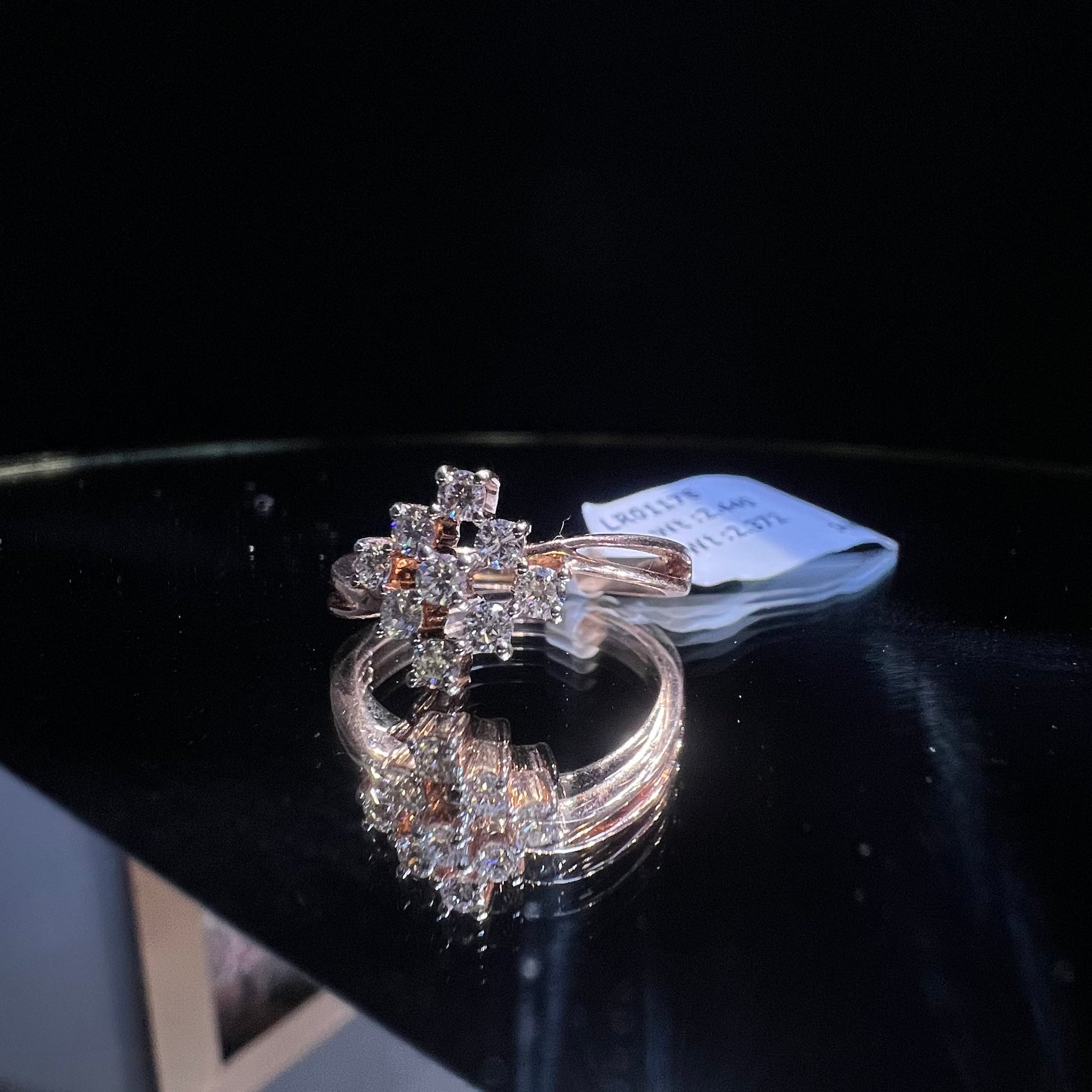 A handcrafted natural diamond solid gold ring, held on a reflective surface, showcasing the ring's design and the shine of the diamonds.