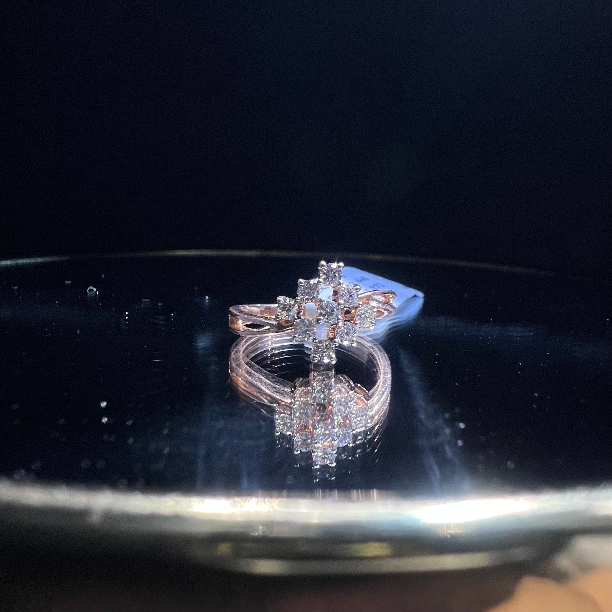 A handcrafted natural diamond solid gold ring, held on a reflective surface, showcasing the ring's design and the shine of the diamonds.