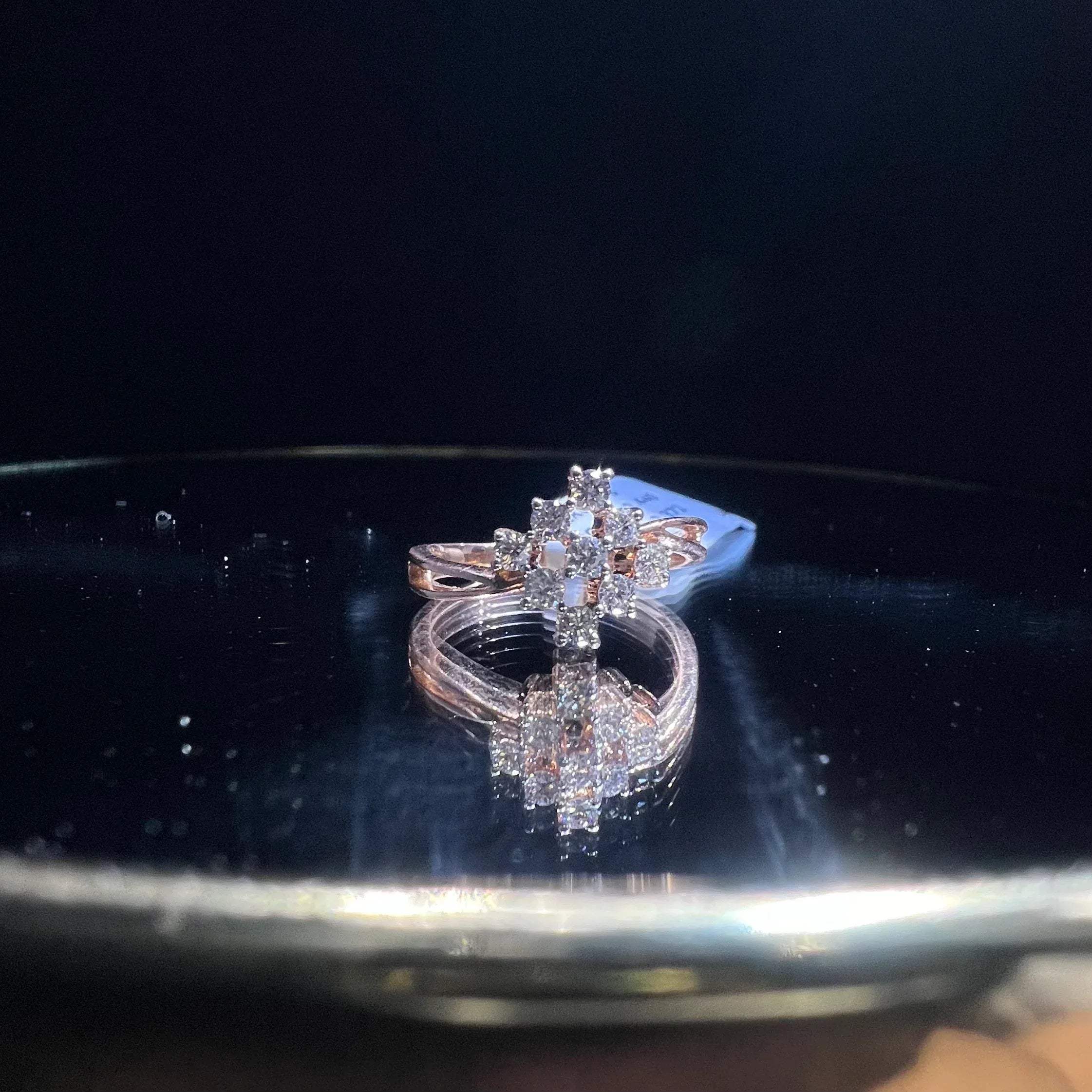 A handcrafted natural diamond solid gold ring, held on a reflective surface, showcasing the ring's design and the shine of the diamonds.