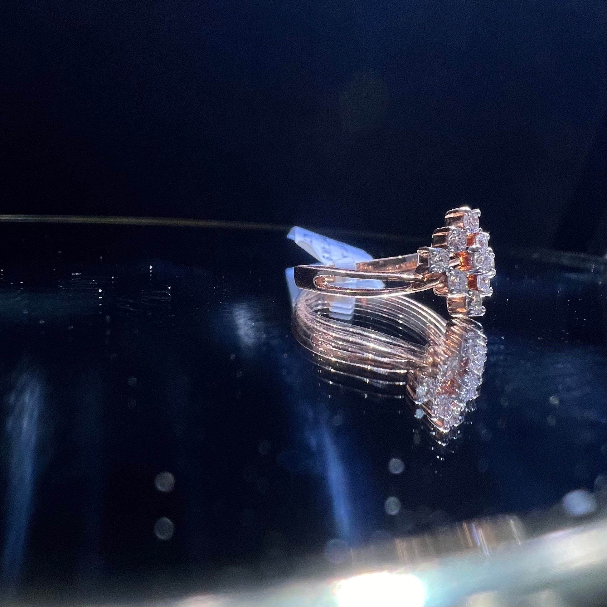 A handcrafted natural diamond solid gold ring, held on a reflective surface, showcasing the ring's design and the shine of the diamonds.