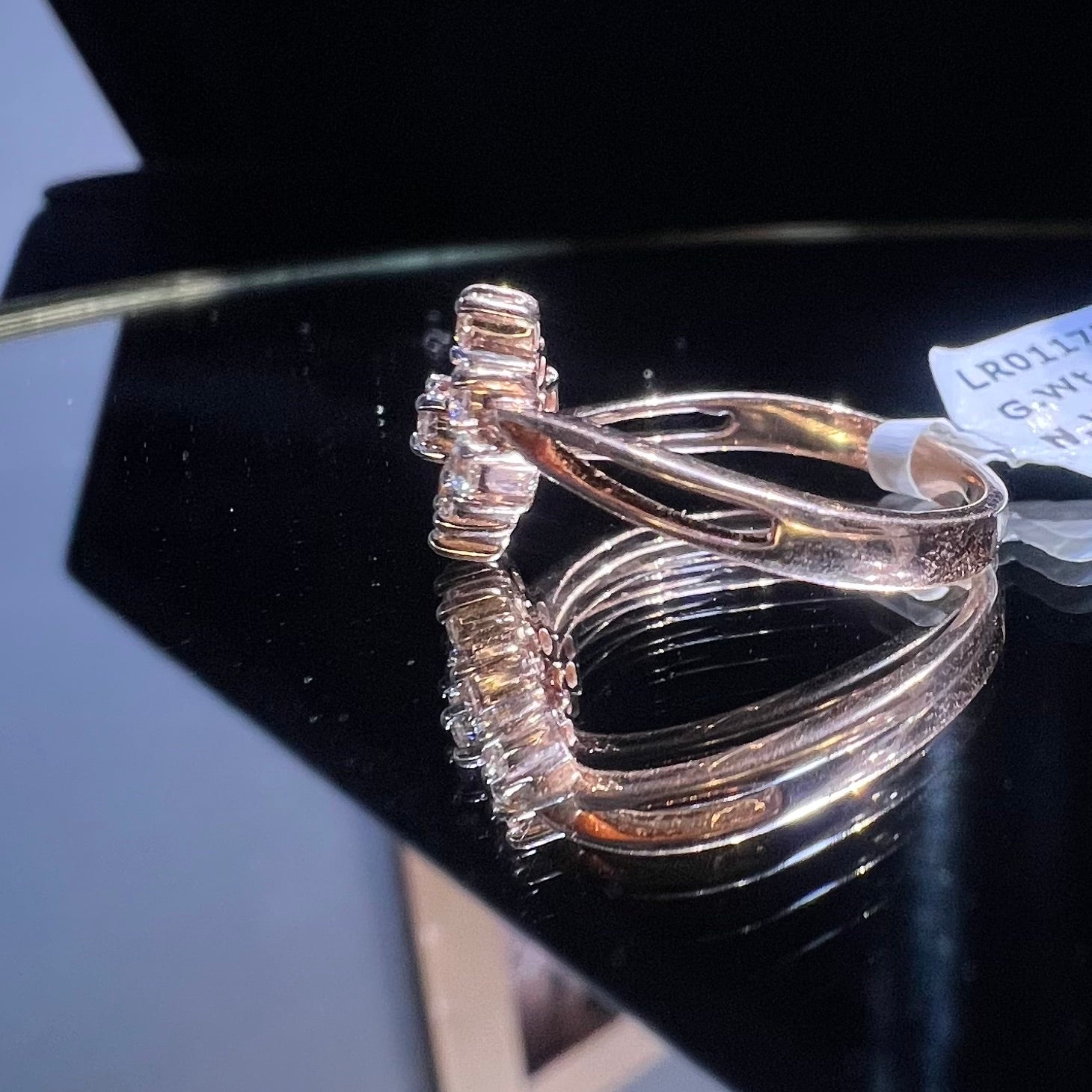 A handcrafted natural diamond solid gold ring, held on a reflective surface, showcasing the ring's design and the shine of the diamonds.