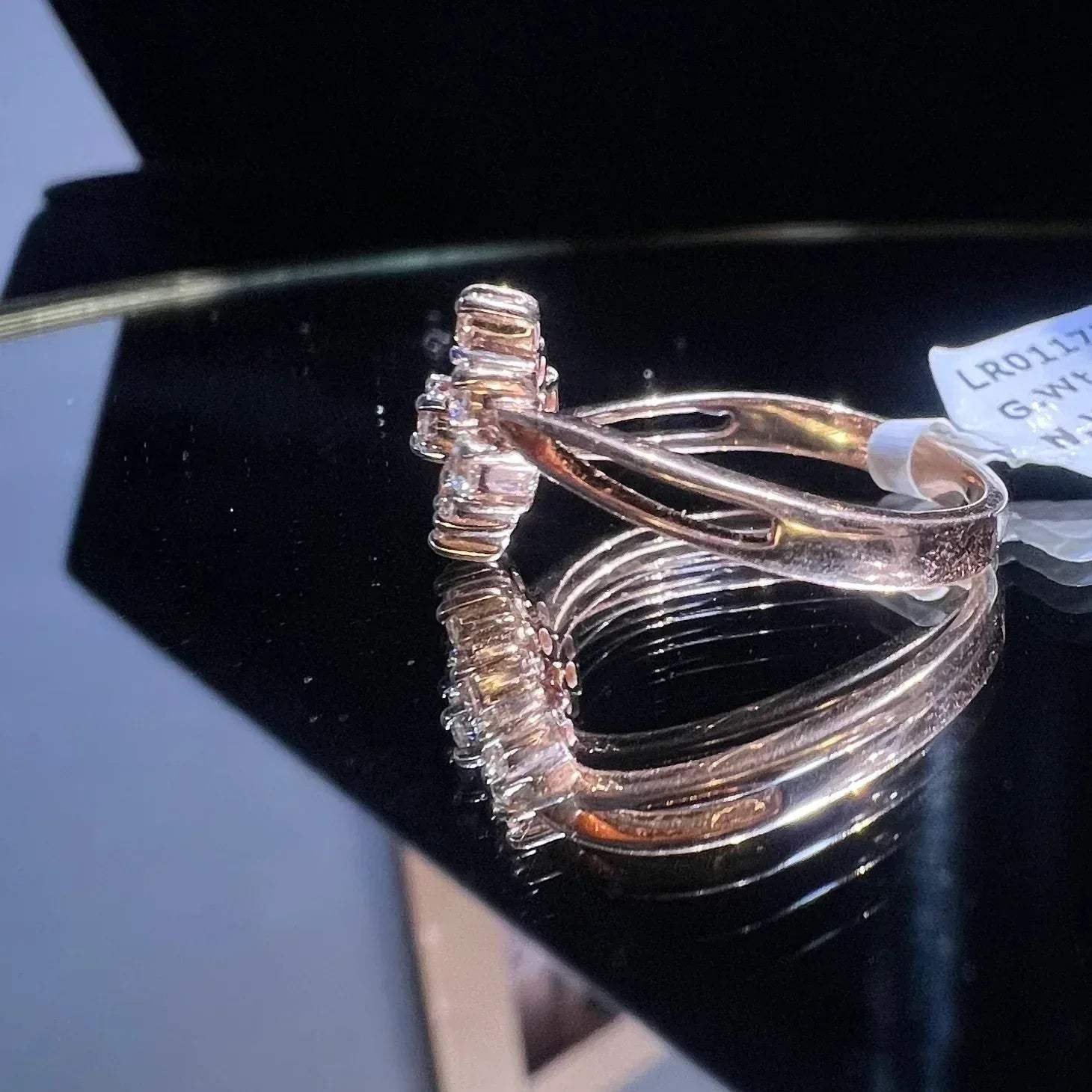 A handcrafted natural diamond solid gold ring, held on a reflective surface, showcasing the ring's design and the shine of the diamonds.