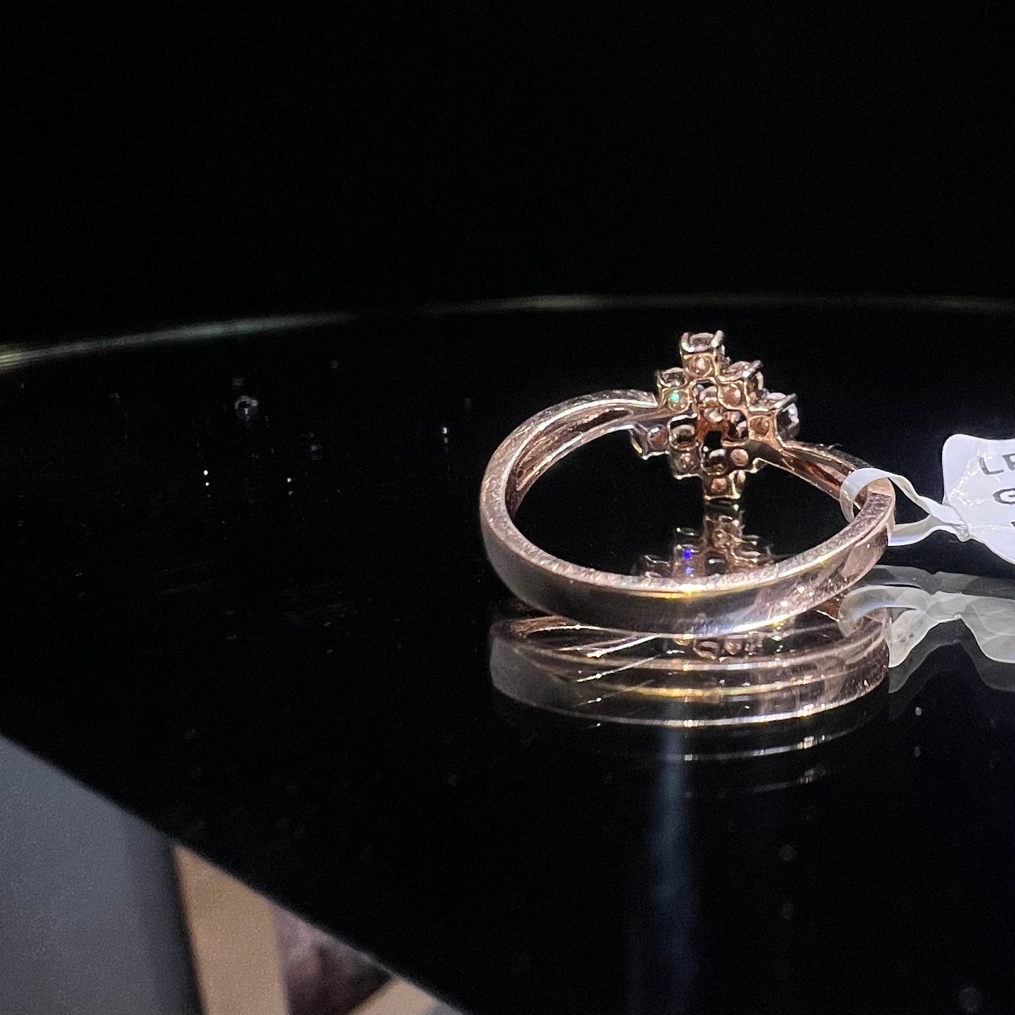 A handcrafted natural diamond solid gold ring, held on a reflective surface, showcasing the ring's design and the shine of the diamonds.