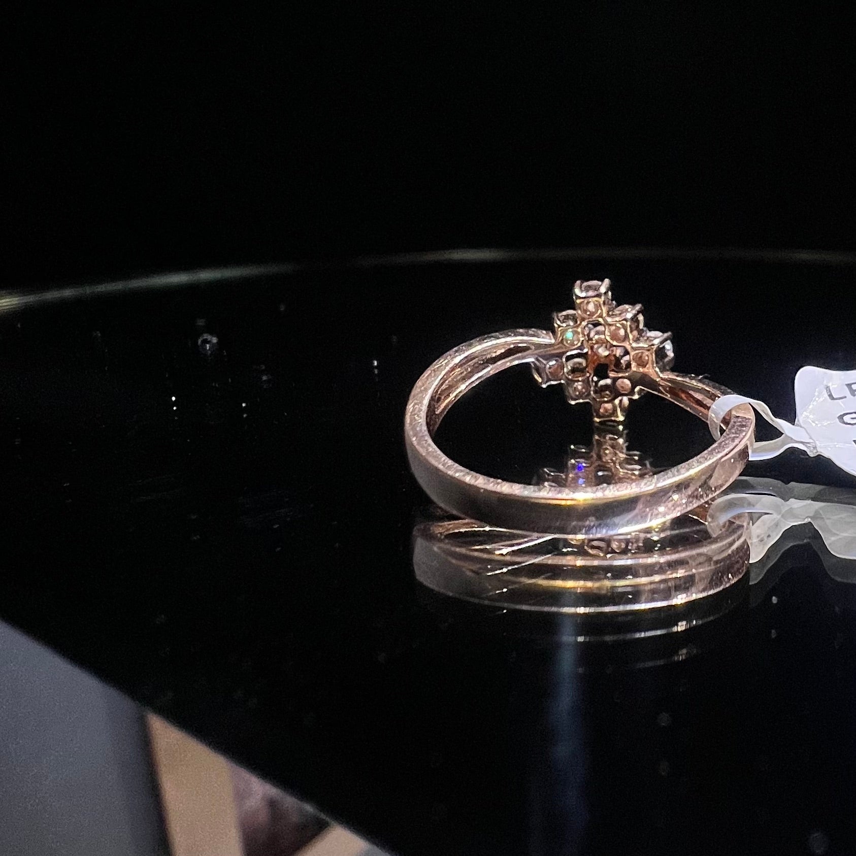 A handcrafted natural diamond solid gold ring, held on a reflective surface, showcasing the ring's design and the shine of the diamonds.