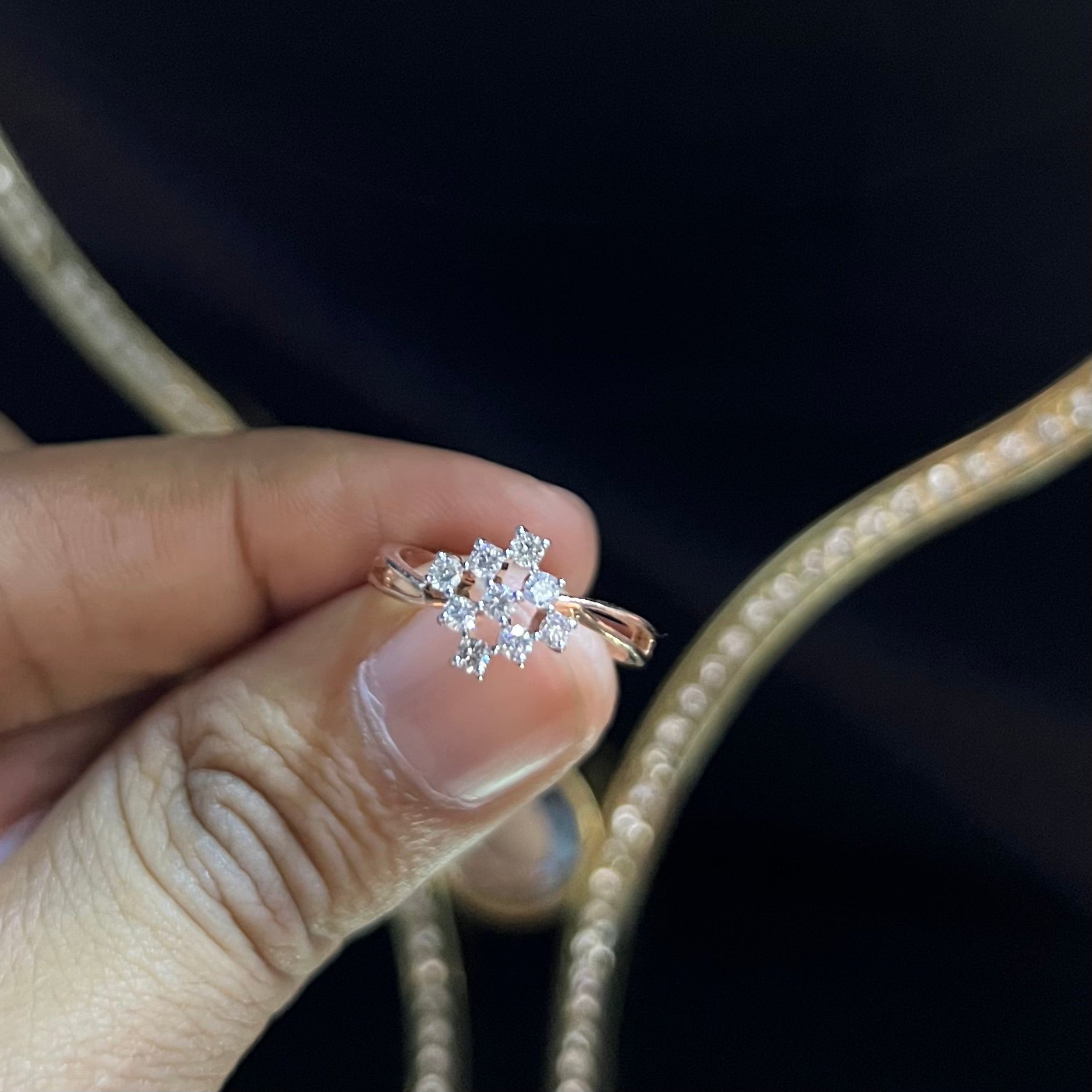 A handcrafted natural diamond solid gold ring, held on a person's hand, showcasing the ring's design and the shine of the diamonds.