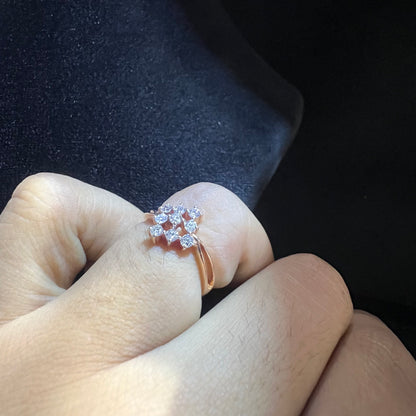 A handcrafted natural diamond solid gold ring, held on a person's finger, showcasing the ring's design and the shine of the diamonds.