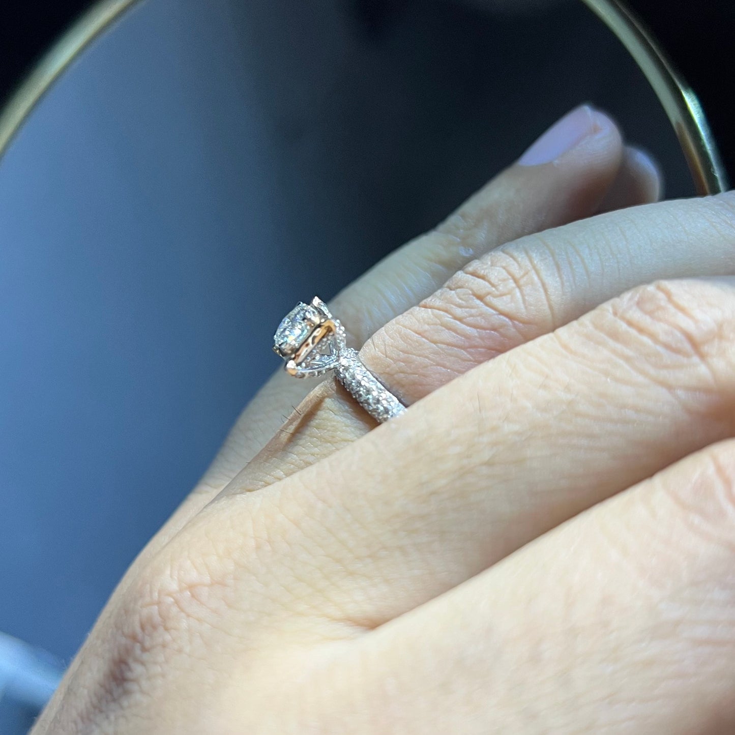 A person's hand displaying a solitaire diamond band ring on their finger.