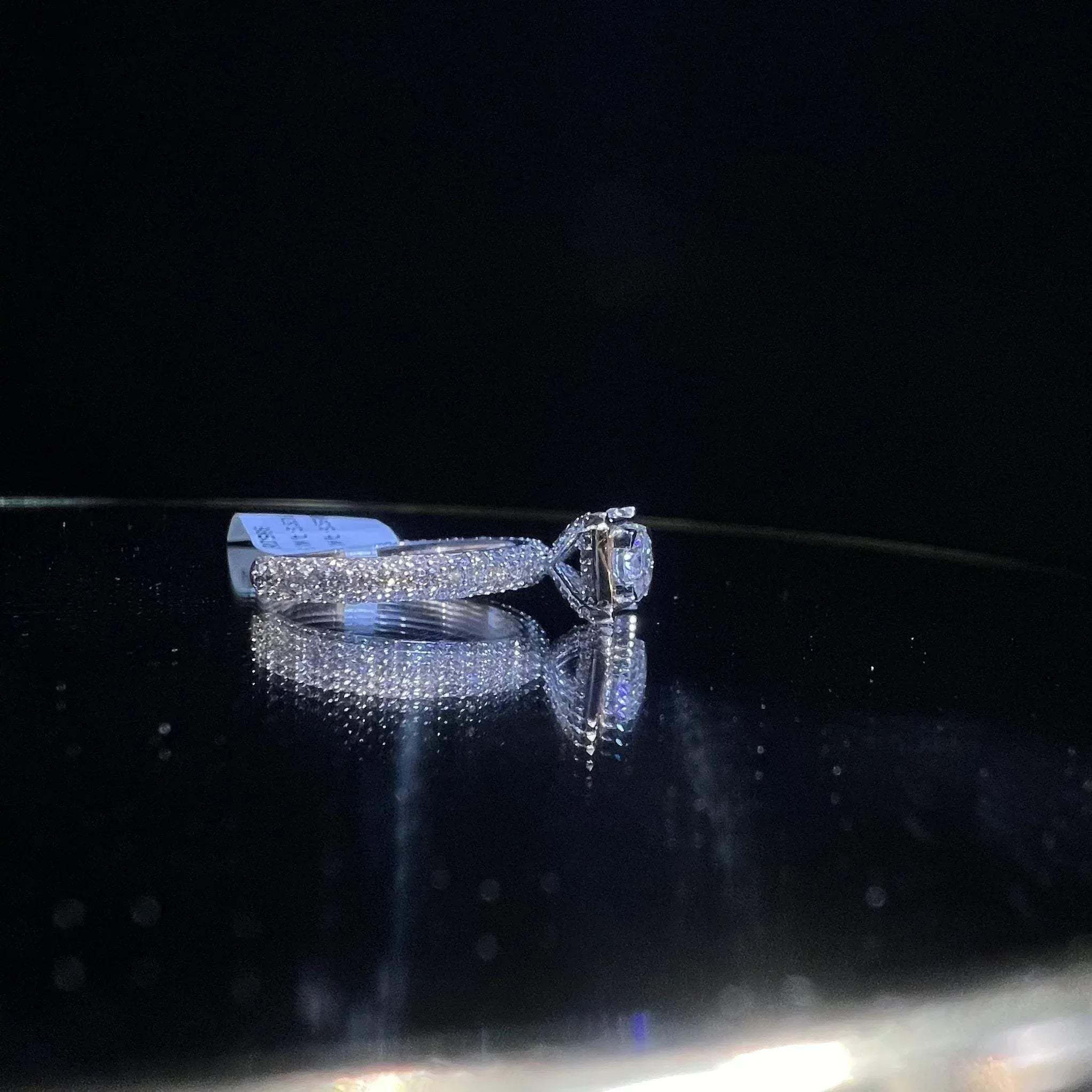 A a solitaire diamond band ring, displayed on a reflective surface.
