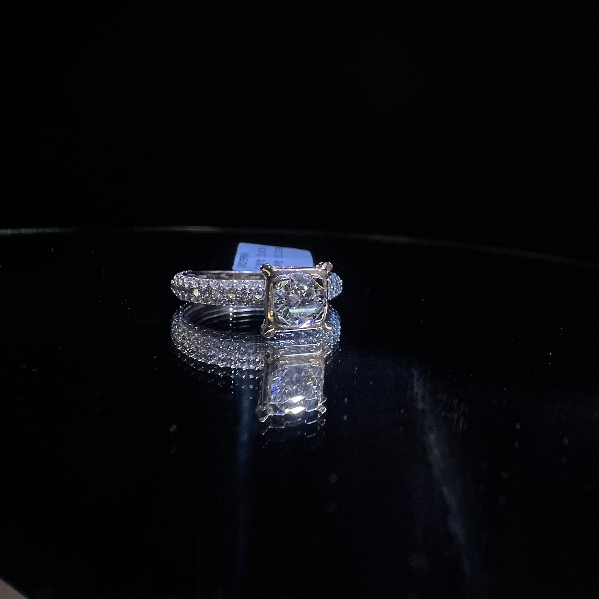 A a solitaire diamond band ring, displayed on a reflective surface.