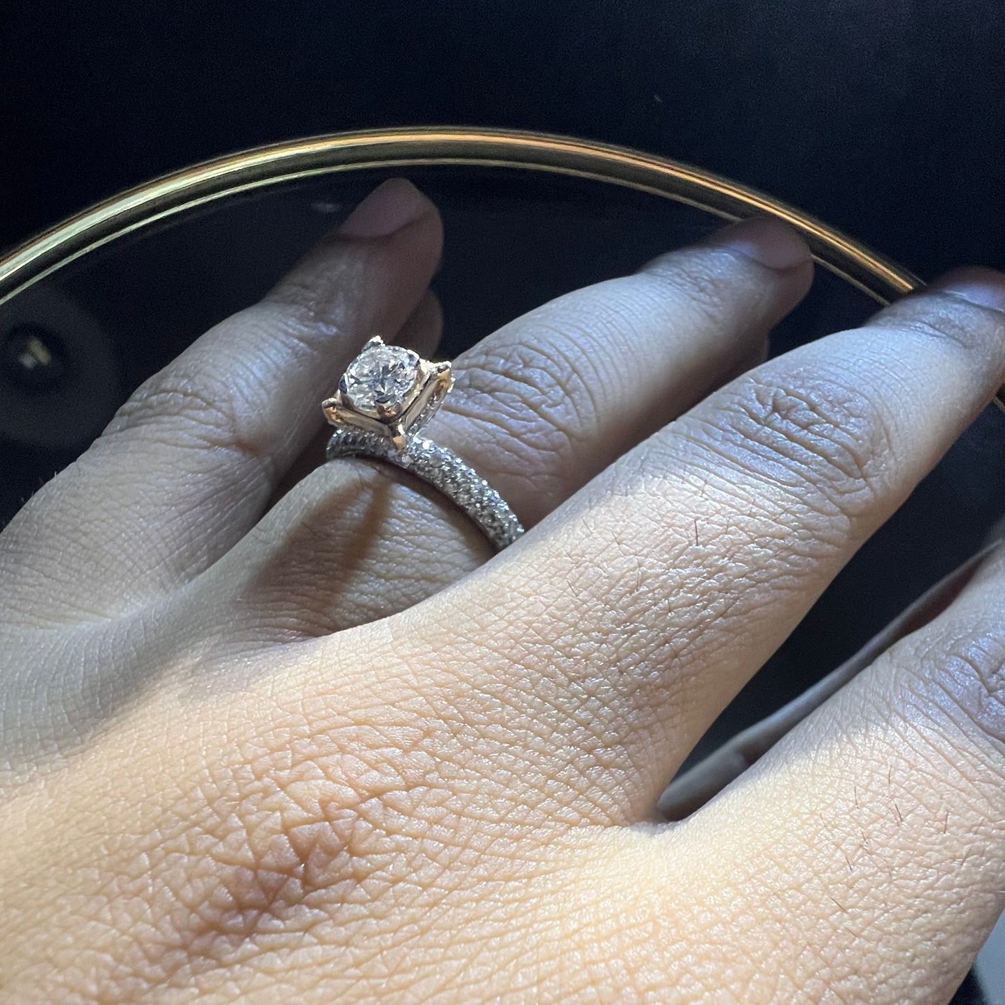 A person's hand displaying a solitaire diamond band ring on their finger.
