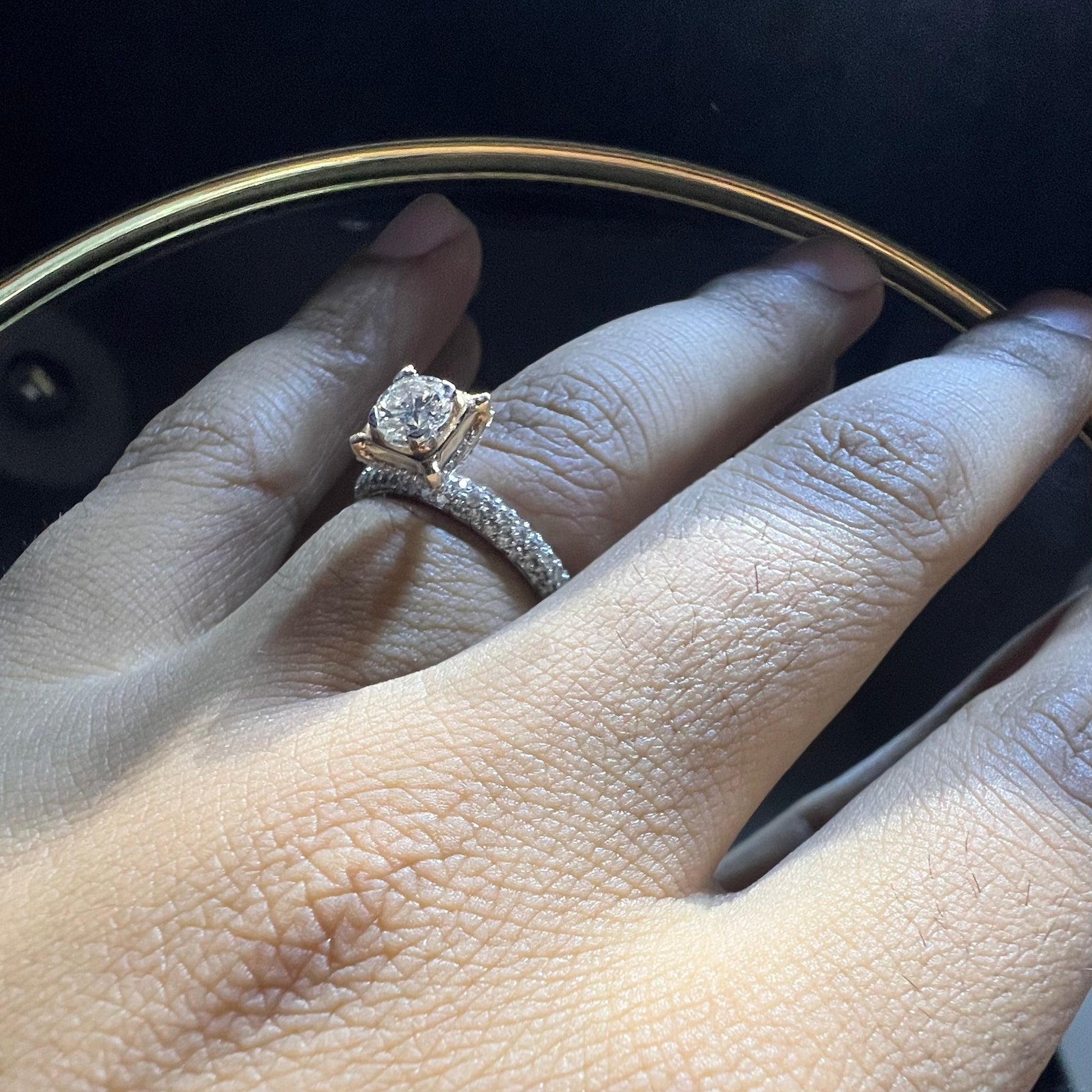 A person's hand displaying a solitaire diamond band ring on their finger.