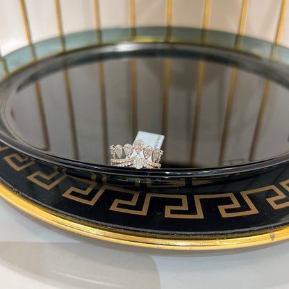 Close-up of a crown-inspired diamond ring featuring multiple baguette-shaped diamonds set upright along the top, paired with a pavé-set band in gold, displayed on a reflective surface.