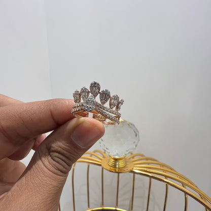 Close-up of a hand holding a crown-inspired diamond ring featuring multiple baguette-shaped diamonds set upright along the top, paired with a pavé-set band in gold, displayed against a gold color cage.