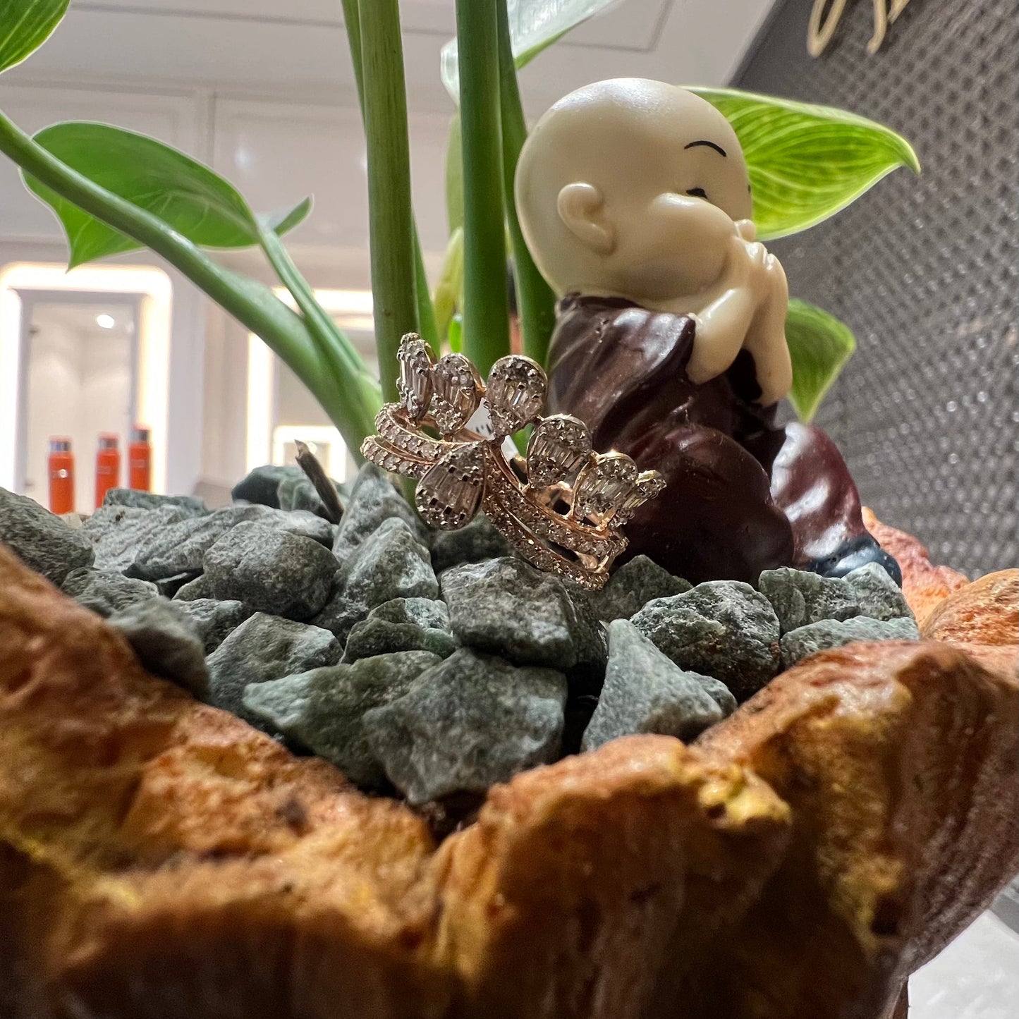 Close-up of a crown-inspired diamond ring featuring multiple baguette-shaped diamonds set upright along the top, paired with a pavé-set band in gold, displayed against a natural background.