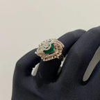 A handcrafted natural diamond solid gold ring held in a person's hand, with a green gemstone and intricate gold detailing.