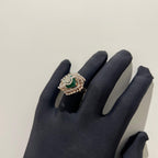 A handcrafted natural diamond solid gold ring held in a person's hand, with a green gemstone and intricate gold detailing.
