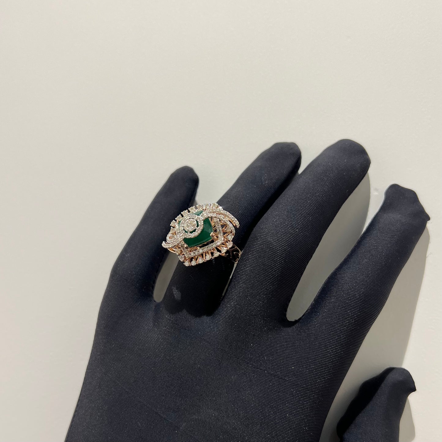 A handcrafted natural diamond solid gold ring held in a person's hand, with a green gemstone and intricate gold detailing.