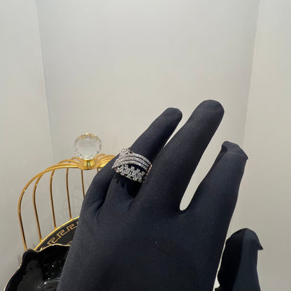 Close-up of an elegant wide diamond ring held by a gloved hand, featuring multiple crisscrossing bands adorned with round-cut diamonds set in gold, displayed against a gold decorative cage background.