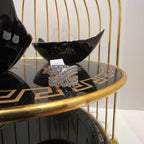 Close-up of an elegant wide diamond ring, featuring multiple crisscrossing bands adorned with round-cut diamonds set in gold, displayed on a black reflective surface.
