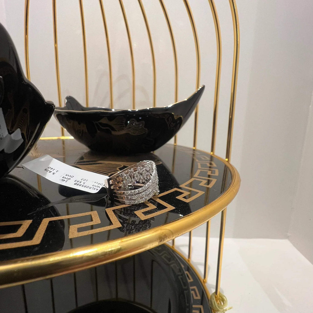Close-up of an elegant wide diamond ring, featuring multiple crisscrossing bands adorned with round-cut diamonds set in gold, displayed on a black reflective surface.
