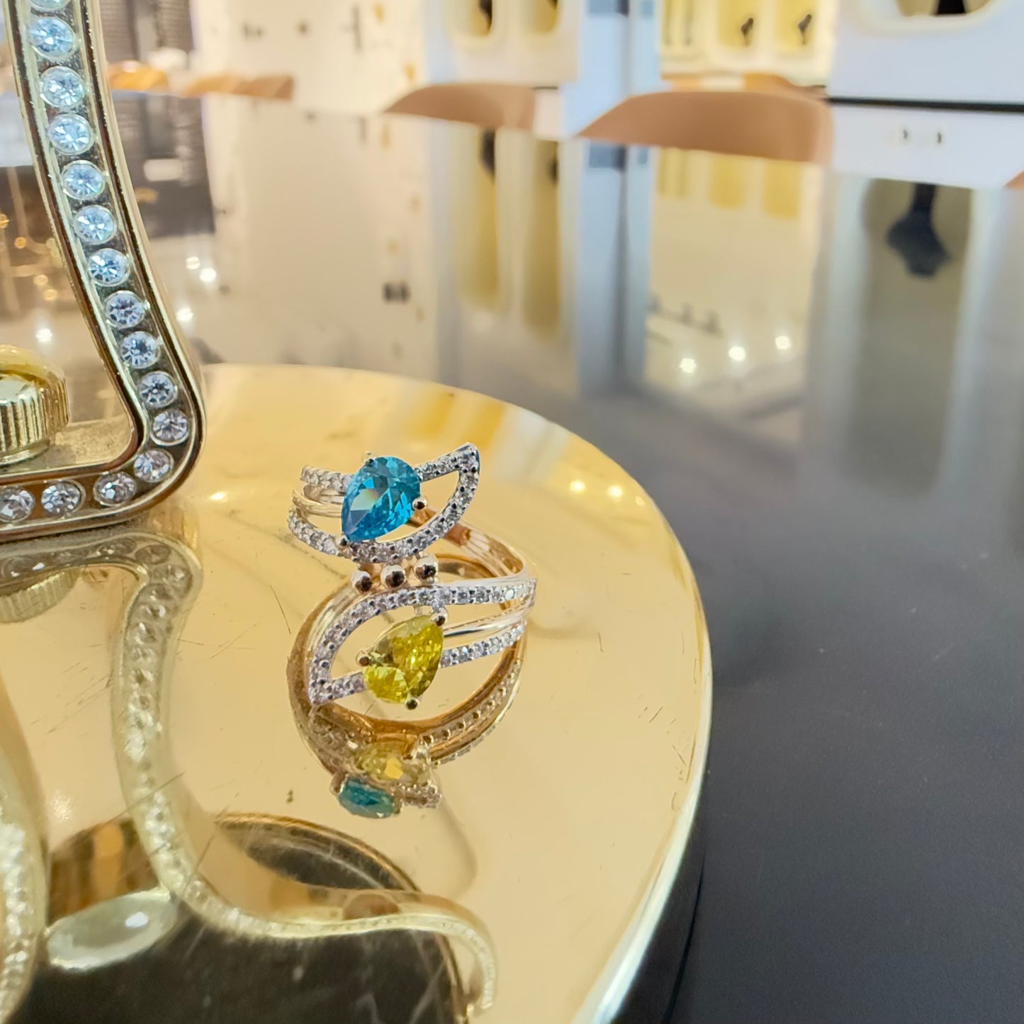 A reflective table displaying a two-stone diamond ring with yellow and blue colors, made of 14kt gold.