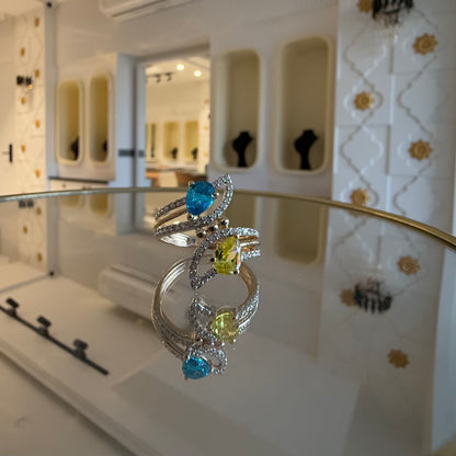 A reflective table displaying a two-stone diamond ring with yellow and blue colors, made of 14kt gold.